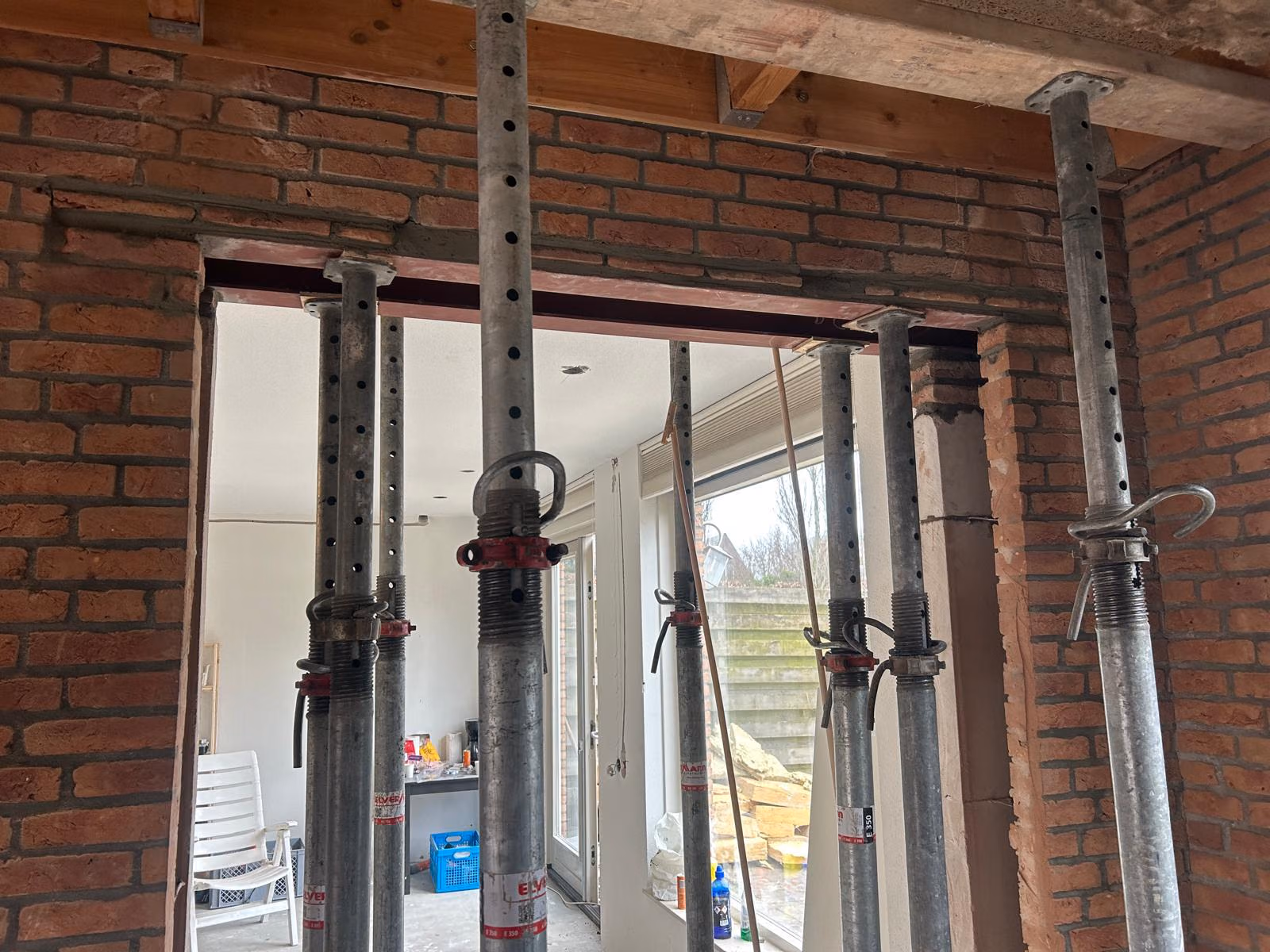 Muurdoorbraak met stalen latei en stempels, een voorbeeld van werk waar bij verbouwen zonder vergunning een constructeur nodig is